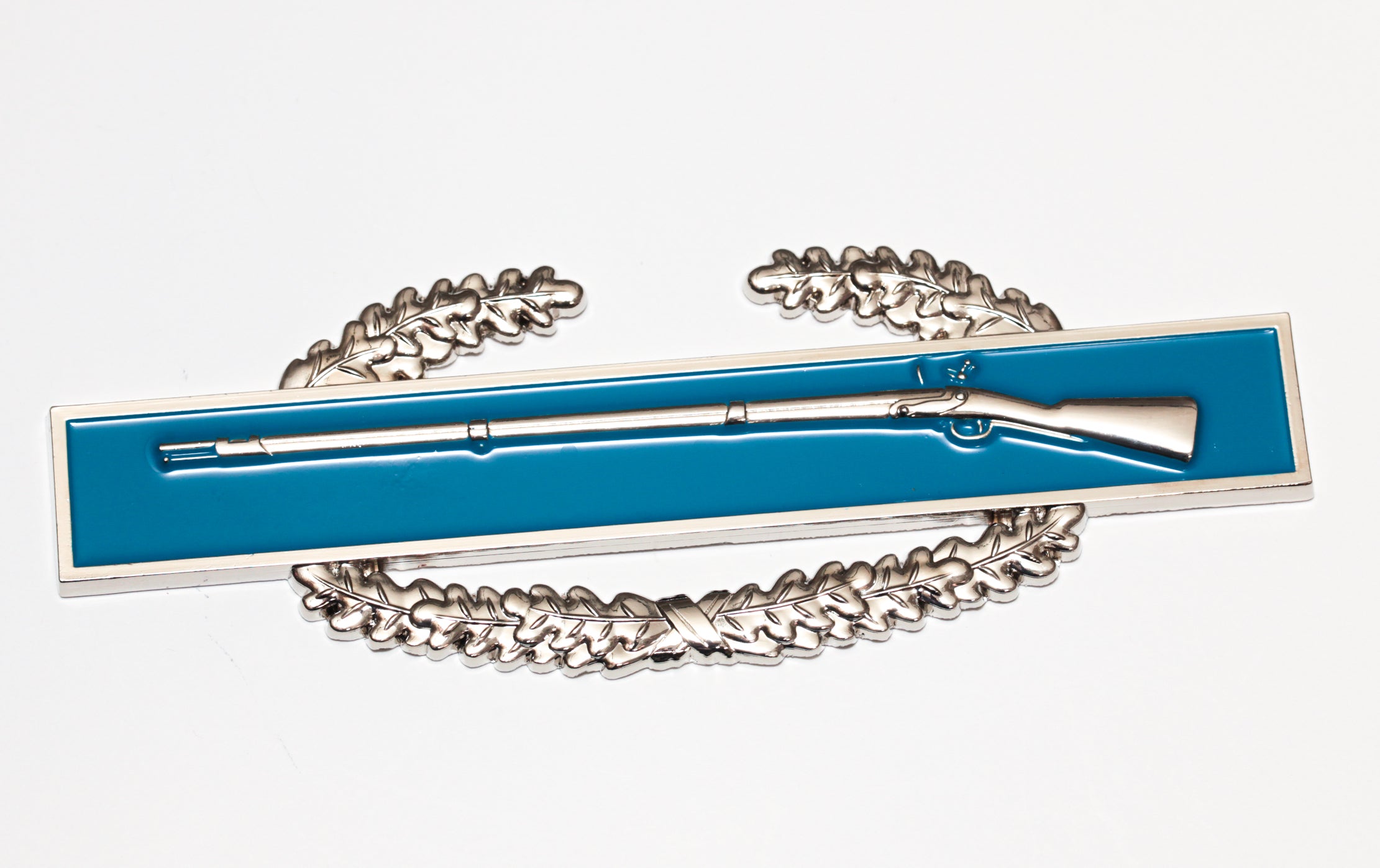 3D sculpted metal Combat Infantry Badge with a rifle design, mounted on a blue and white display stand.