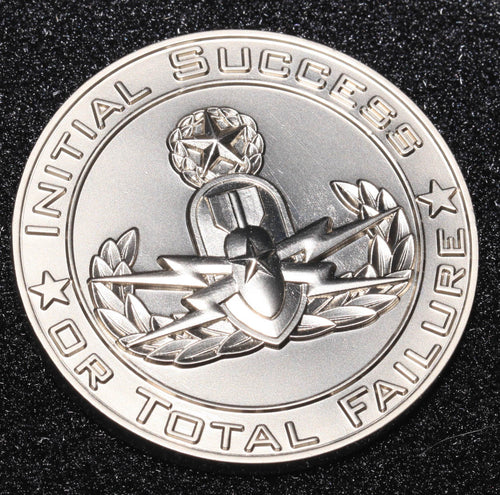 A collectible coin with an inscription 'Initial Success or Total Failure' and a graphic of a rabbit wearing a top hat.