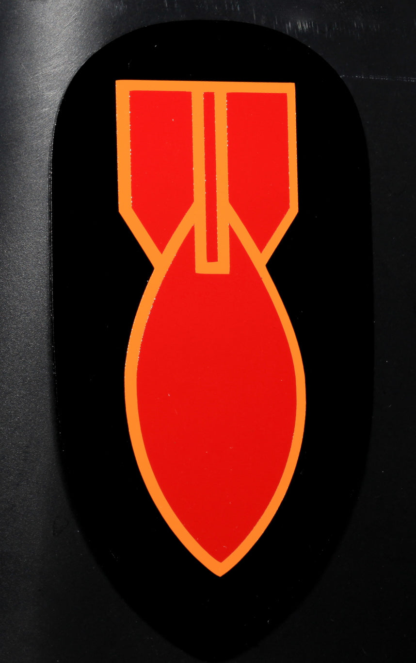 A vinyl decal featuring a red and yellow bomb design with a black tip, indicating it is a World War II era bomb disposal patch.